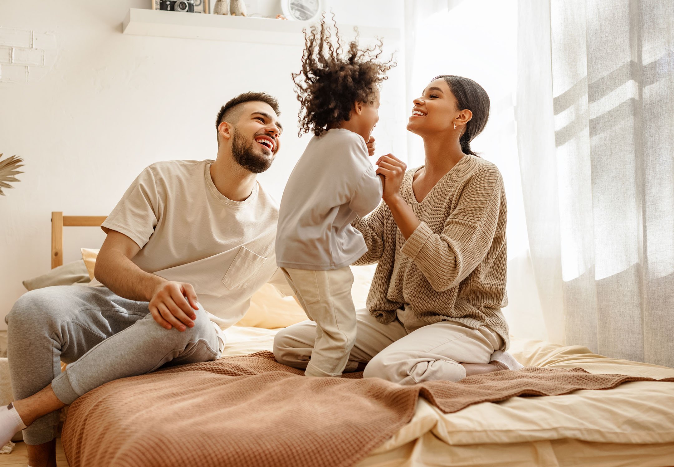 Happy young family plays in the morning in comfortable warm home