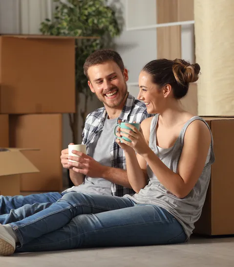 Happy young homeowners relax next to move-in boxes