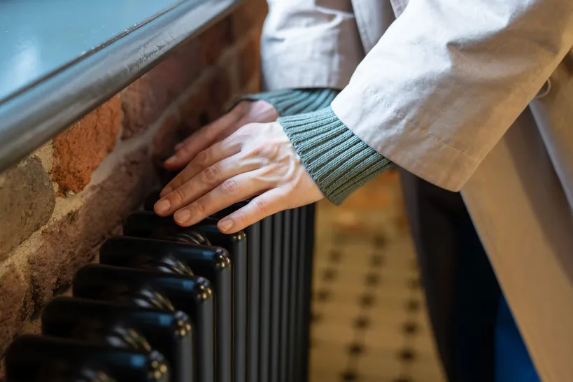 hands over a cold radiator in an old apartment