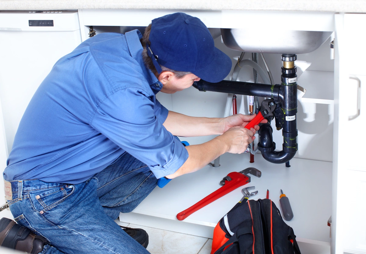 plumber using hand tools to fix a sink drain