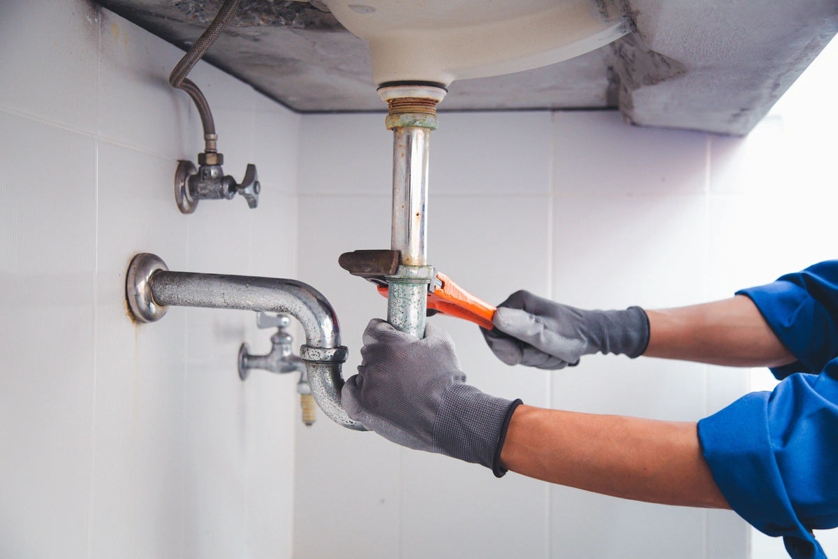 sink drain being serviced underneath the sink with a hand tool