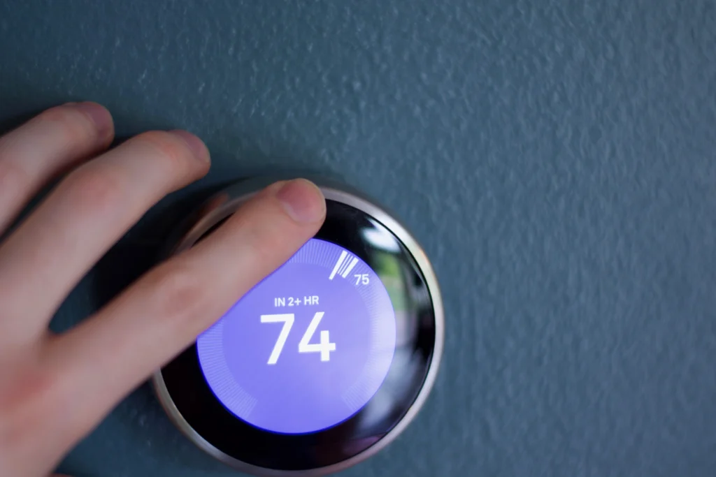 furnace installation-hand adjusting the dial of a thermostat