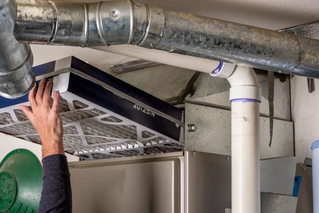 furnace installation-person's hand replacing a furnace filter
