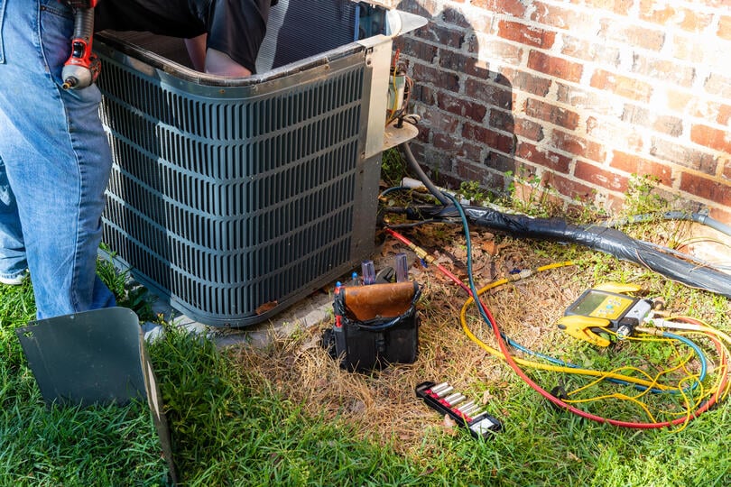 ac condenser-technician performing maintenance on an ac unit