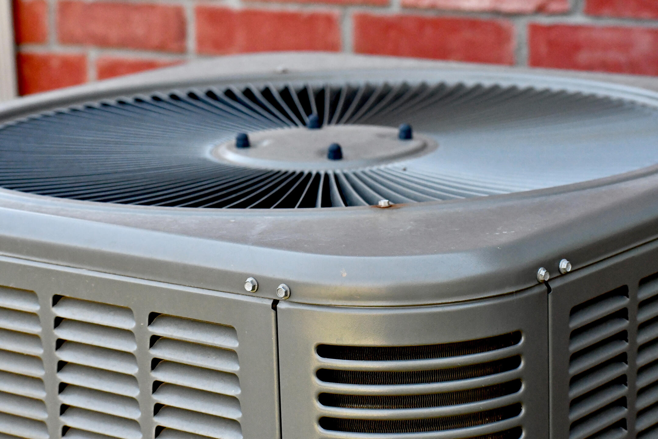 ac unit cost-close up image of a new AC unit next to a brick house