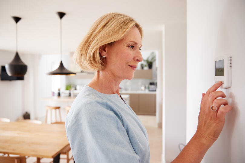 how does ac work-woman adjusting her thermostat