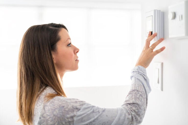 thermostat not working-woman trying to adjust her thermostat
