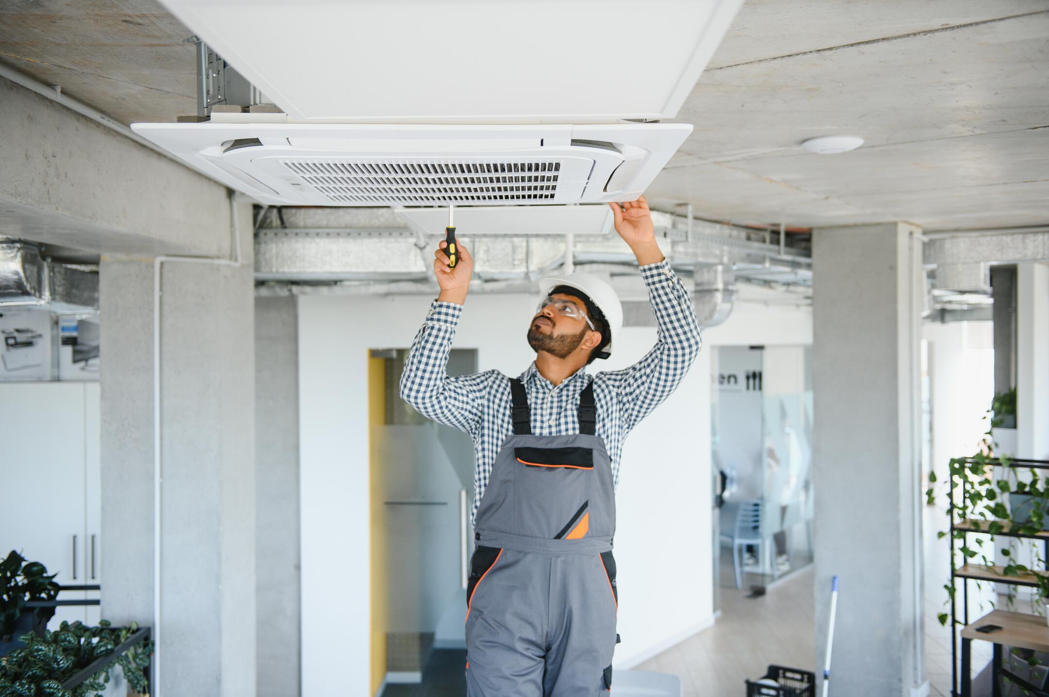 ac tune up cost-technician inside a home checking interior components of HVAC unit