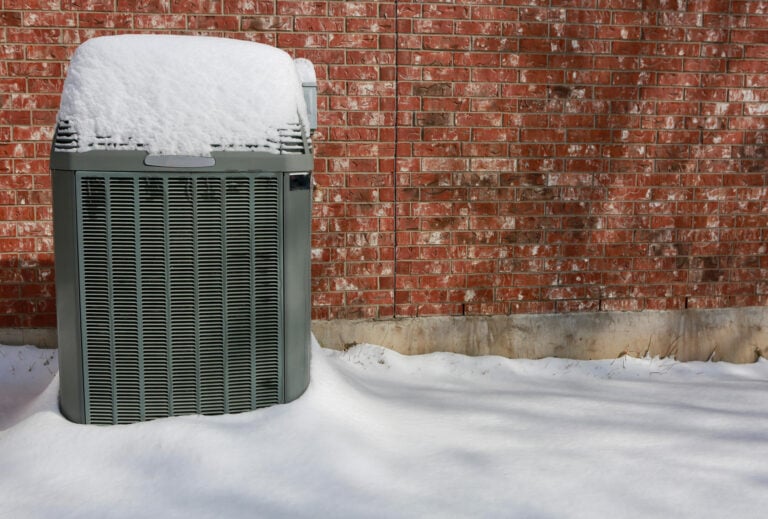 how does a heat pump work in winter-gray heat pump outside a brick house