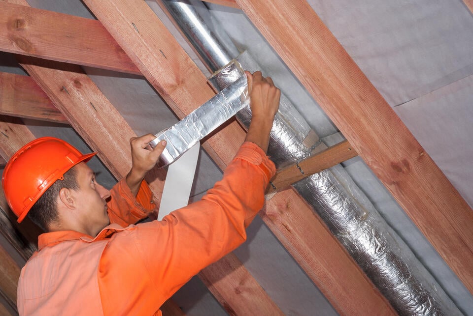 pipe insulation-tech wrapping large pipes in insulation materials between rafters