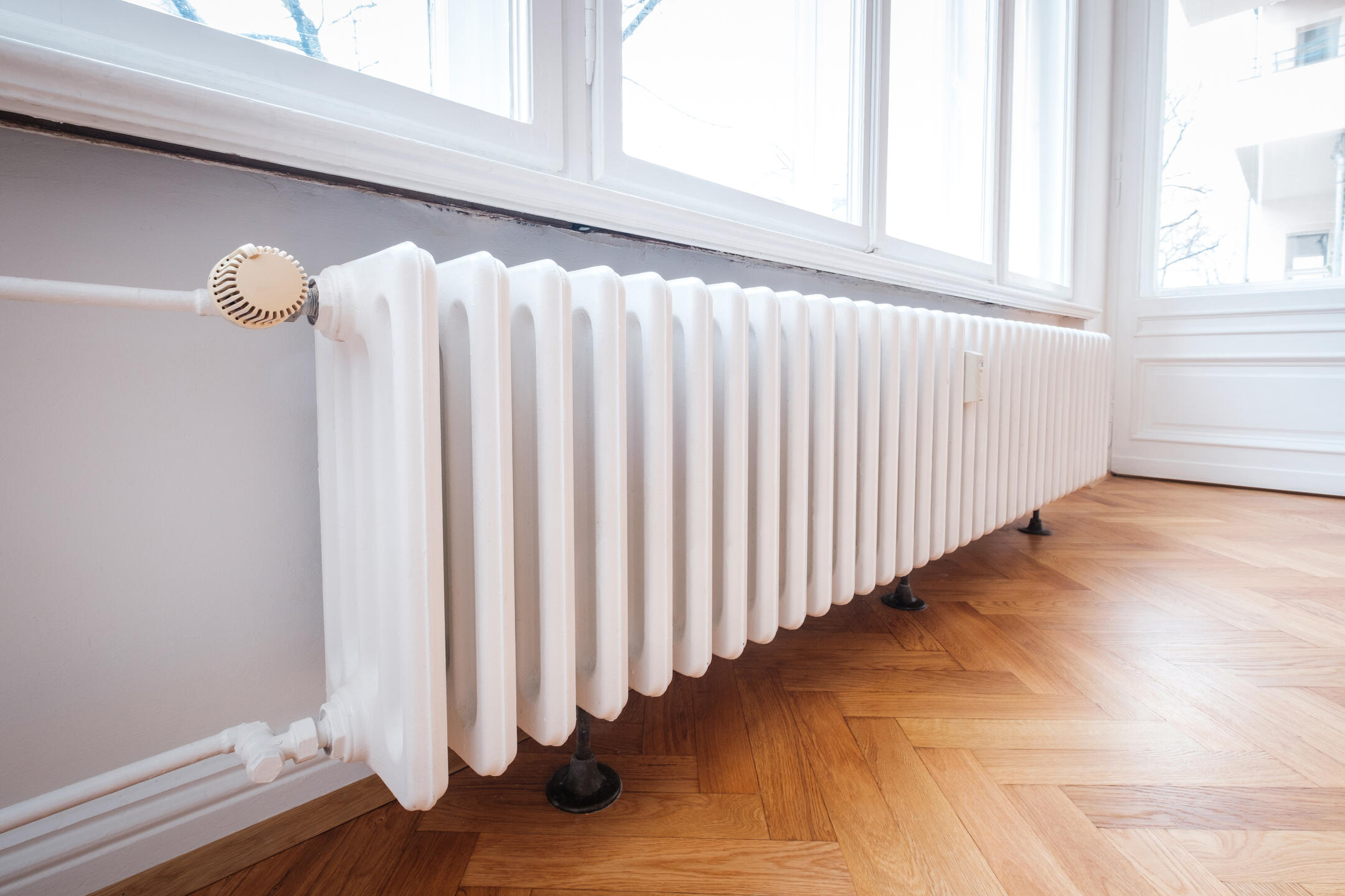 radiator heater-white radiator on wood flooring beneath a window