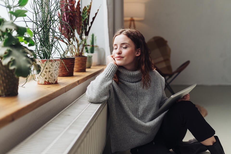 radiator heater-woman enjoying the heat from a radiator near a window