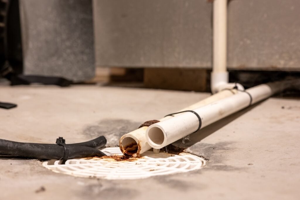 Selective focus on a residential house basement floor drain with furnace and water softener drain lines