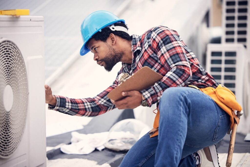 Technician, clipboard or air conditioning inspection on rooftop for safety, power or maintenance. Electrician, black man or paperwork on hvac system, ac repair or quality assurance for sustainability. hvac companies big lake