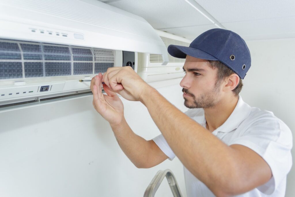 portrait of mid-adult male technician repairing air conditioner ac unit parts