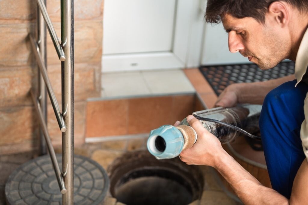 Worker performs the installation of pumping equipment. Sewer cleaning