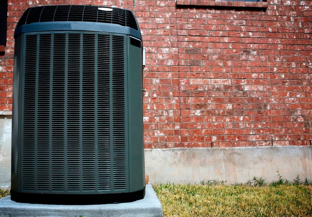 why is my ac leaking water High efficiency modern AC-heater unit, energy save solution in front of brick wall